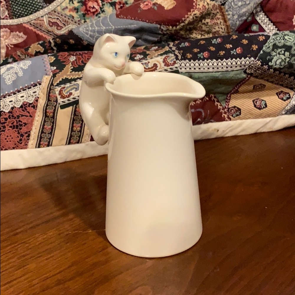 Kitten climbing pitcher of cream